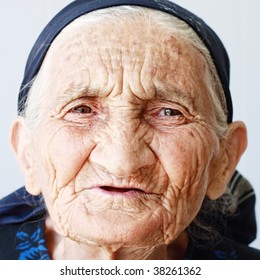 Very old hoary woman face closeup portrait against light background