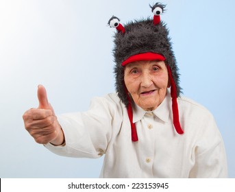  very old lady in funny fur hat with two tentacles showing thumbs up