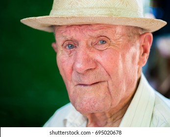 Very Old Man Boomer Portrait With Emotions. Grandfather Happy And Smiling. Portrait: Aged, Elderly Senior. Close-up Of A Pensive Old Man In White Hat Sitting Alone Outdoors At Summer.