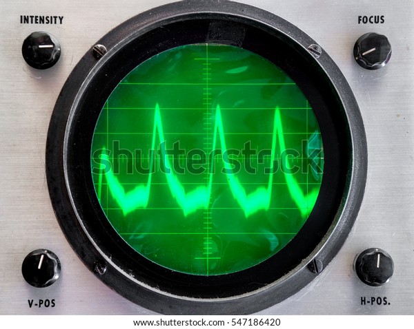 Very old\
oscilloscope. Round face is green plastic film that is not even,\
somewhat dirty. Fuzzy trace on display shows peaks. Controls in\
each corner.  Focus on grid in\
center.