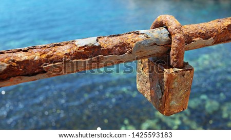 A very old and rusty love lock or padlock  on a section of the chain link fence, symbol of unbreakable love and lifetime commitment for the couples who decided to eternally lock their hearts together