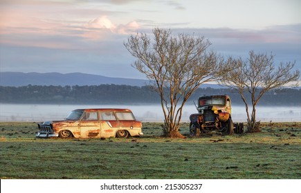 Very Old Vintage And Rusty Truck And Car Sit Undisturbed In A Field And Catch The First Rays Of Sunlight On A  Misty Foggy Frosty Morning In The Country.  Richmond NSW Australia