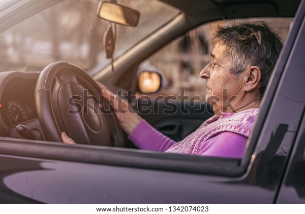 Very\
old woman driving car. Active senior woman - smiling retired lady\
driving car. Confident senior woman driving a car.\
