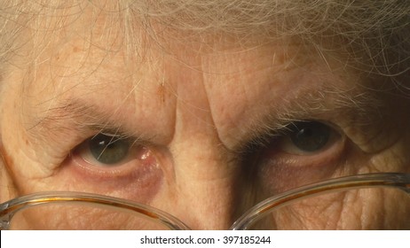 A Very Old Woman Puts On Glasses And Looking At The Camera