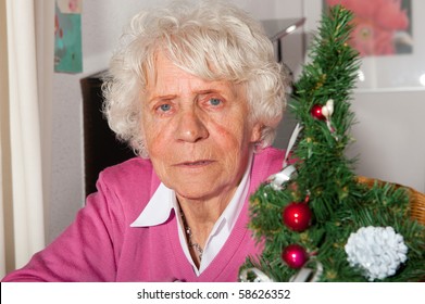 Very Old Woman In Sitting Near A Christmas Tree