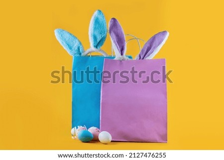 Very peri, blue shopping bag, rabbit ears and Easter eggs. Online shopping for the holidays. Symbols, traditions concept. Trending color of the year for Easter.
