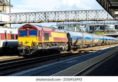 A very powerful freight train pulling it's loaded carriages past a station platform, in the United Kingdom.