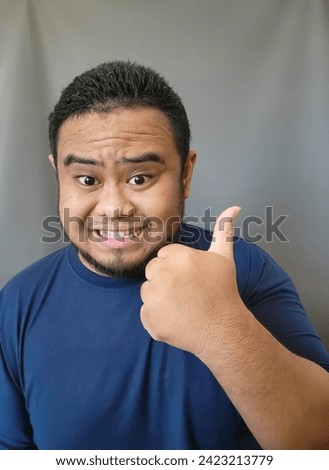 A very random pose of Asian men wearing blue t-shirts on a gray background. random theme.