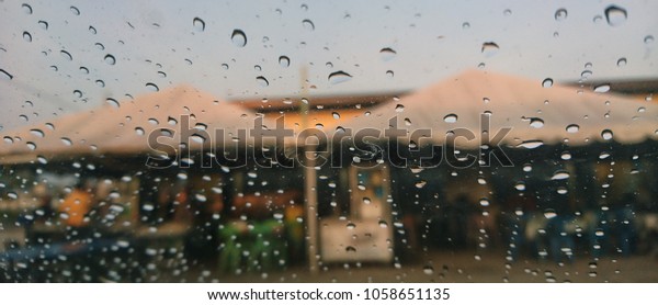 A very\
rare rainy day with car and people as seen through car windows with\
rain drops visible on the window. Blured background with rains drop\
on glass and cars on the road.- soft focus \

