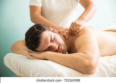 Very relaxed young Latin man getting a deep tissue massage on his back in a wellness and spa clinic