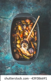 Very Rustic Roasted Vegetables Stew Or Ragout With Wild Game And Wild Fowl And Forest Mushrooms In Black Backing Dish With Wooden Cooking Spoon On Dark Aged Background, Top View. Country Food