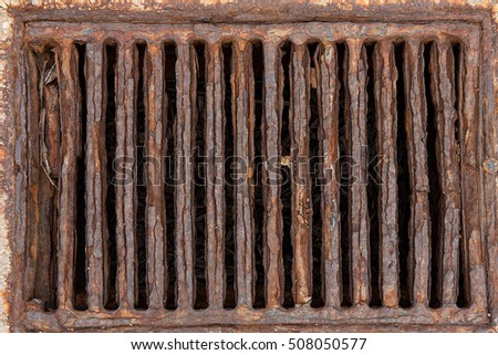 Very rusty and old iron grid covering a drain,  Exposed to salty sea air. Corroded, good brown colours