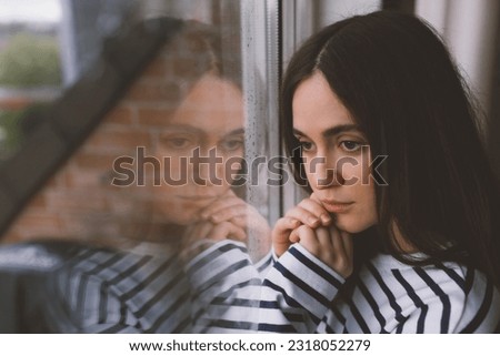 Very sad lonely girl. Depression and worried woman at home. Upset lady looking at the window. 