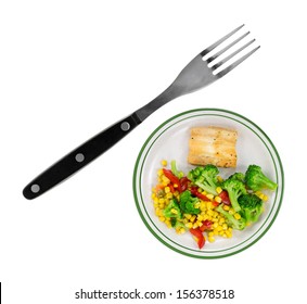 A Very Small Diet Meal Of Haddock And Vegetables With An Over Sized Fork To The Side.