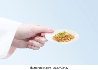 Very small portion of noodles. Miniature plate with vegetarian food in hand. 