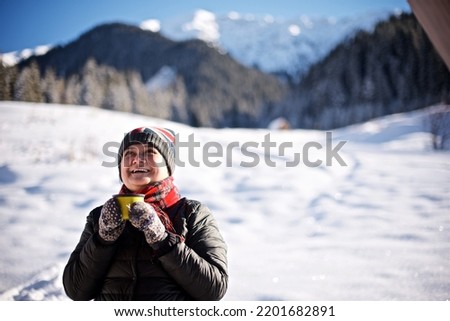 Very smiling asian senior woman is enjoying her hot tea outdoor in the winter nature