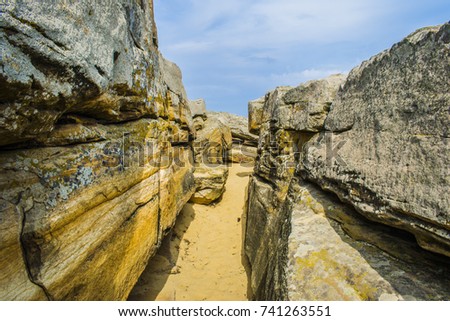A very thin passage between the stone giants. Stones and sand of yellow color