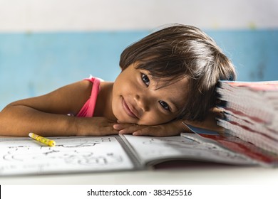 a very young girl student in the school has her head on the exercise book and smiling friendly. Thai school in a small village