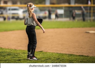 Very Young Girl in Uniform Standing in Outfield