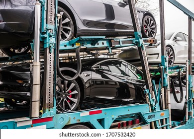 Vestal, NY/USA - April 11, 2020: A semi-tracker trailer hauling seven Tesla Models 3 and X, painted white, black and silver, sits parked overnight in a parking lot over Easter weekend. 
