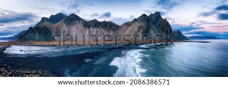 Vestrahorn mountain panorama. High angle drone shot across the black beach and sand dunes at sunset. Stokksnes peninsula, southeast Iceland