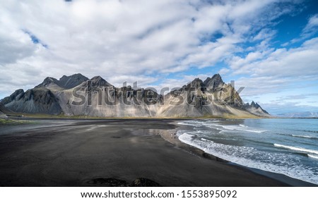 vestrahorn in southern Iceland, mirroring in calm water over black volcanic beach, landscape photography 