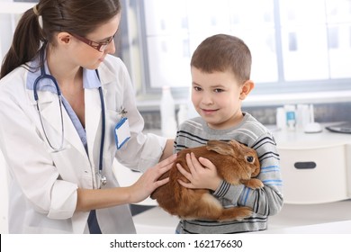 Vet Helping Little Kid Holding Cute Pet Rabbit At Pets' Clinic.