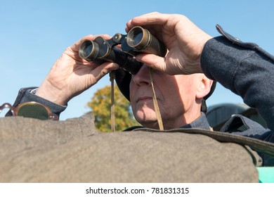 Veteran male military personnal peering through a pair of binoculars outdoors - Powered by Shutterstock