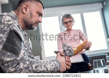 Veteran soldier having therapy meeting with senior female psychologist.
