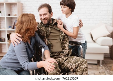 The Veteran In A Wheelchair Came Back From The Army. Wife And Son Are Glad To See Him. A Man In Uniform In A Wheelchair With His Family.