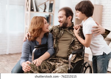 The Veteran In A Wheelchair Came Back From The Army. Wife And Son Are Glad To See Him. A Man In Uniform In A Wheelchair With His Family.