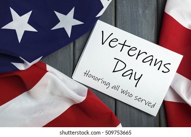Veterans day 11th November. Veterans day. Honoring all who served. Printed on sheet of paper. American (USA) flag on wooden background.