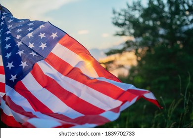 Veterans Day Flag Of The United States Of America. American flag flying on the background of the setting sun in nature.