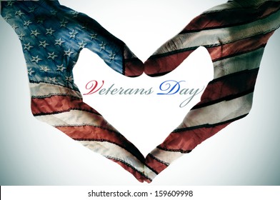 veterans day written in the blank space of a heart sign made with the hands patterned with the colors and the stars of the United States flag