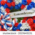 A Veterans memorial wreath with red, white, and blue silk flowers and an "In Remembrance" banner. Closeup.