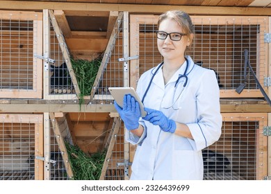 Veterinarian woman with tablet computer checking animal health status on barn ranch background. Vet doctor check up rabbit in natural eco farm. Animal care and ecological livestock farming concept - Powered by Shutterstock