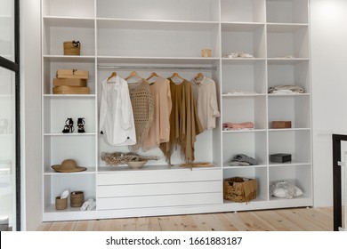 Vew on minimalistic scandinavian white wood walk in closet with wardrobe in neutral beige colors