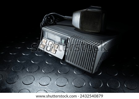 VHF transceiver often used by law enforcement and first responders with a  microphone laying on top.