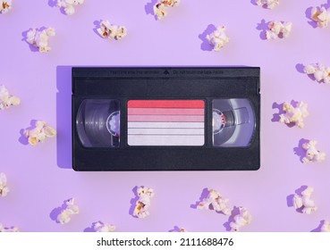 VHS video cassette and a lot of popcorn. Flat lay bright composition with neon light. Aesthetics of retro style.