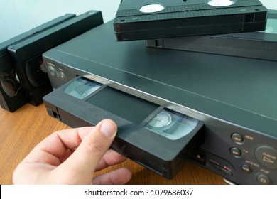 VHS videocassette is put into the video recorder to watch the video, another video cassette is on the video-tape recorder