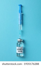 Vial Of Covid - 19 Vaccine And Syringe On Blue Background