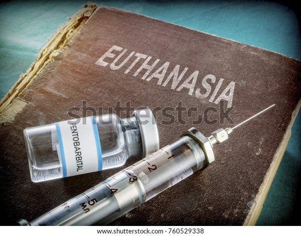 Vial and vintage syringe with medicine\
on an old book of euthanasia, conceptual\
image