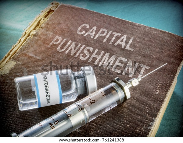  Vial And Vintage Syringe With\
Medicine On An Old Book Of Capital Punishment, Conceptual\
