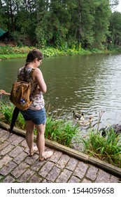VIANOPOLIS - BETIM, MINAS GERAIS / BRAZIL - JANUARY 2, 2016: A young woman feeding some ducks at the edge of one of the lakes of Vale Verde - Alembic and Ecological Park.