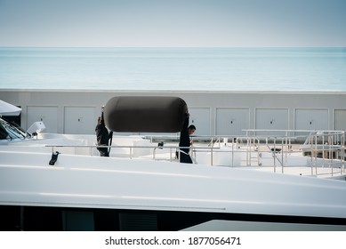 Viareggio, Italy - November 26, 2020: Two deckhands moving a big fender along the foredeck of a superyacht leaving the port