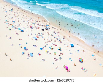 A vibrant aerial view of people at the beach on a busy summer day in Surfers Paradise on the Gold Coast in Queensland, Australia with