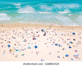 A vibrant aerial view of people at the beach on a busy summer day in Surfers Paradise on the Gold Coast in Queensland, Australia with turquoise water