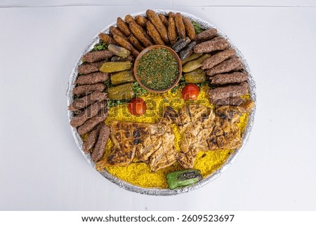 A vibrant and appetizing Arabic feast served on a large round tray, featuring grilled chicken breasts, juicy kofta kebabs, mahshi (stuffed zucchini, eggplant, and grape leaves), roasted vegetables, an