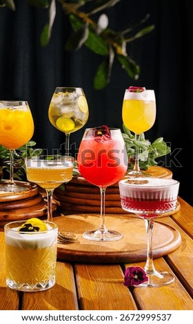 A vibrant array of cocktails is presented on round wooden coasters. Each drink is garnished with fresh fruits and flowers, showcasing a lively bar atmosphere perfect for social gatherings.