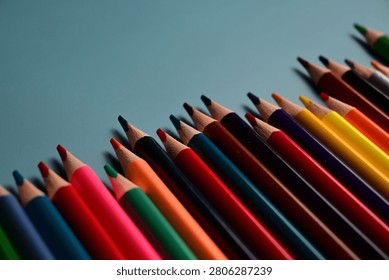 A vibrant array of colored pencils aligned diagonally on a blue background, showcasing a spectrum of colors.